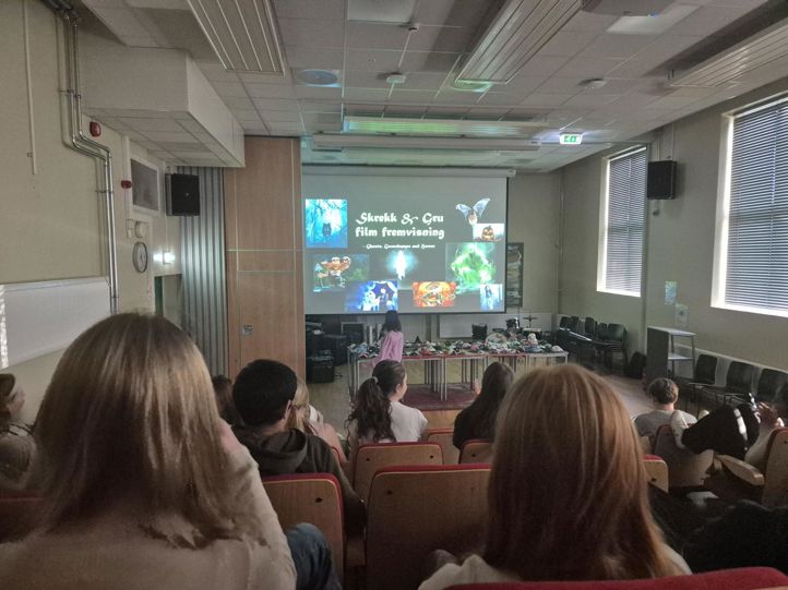 en gruppe mennesker som sitter i et rom og ser på en skjerm